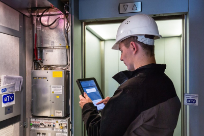 Afbeelding van een liftmonteur in de lift met een witte helm op Afbeelding van een liftmonteur in de lift met een witte helm op